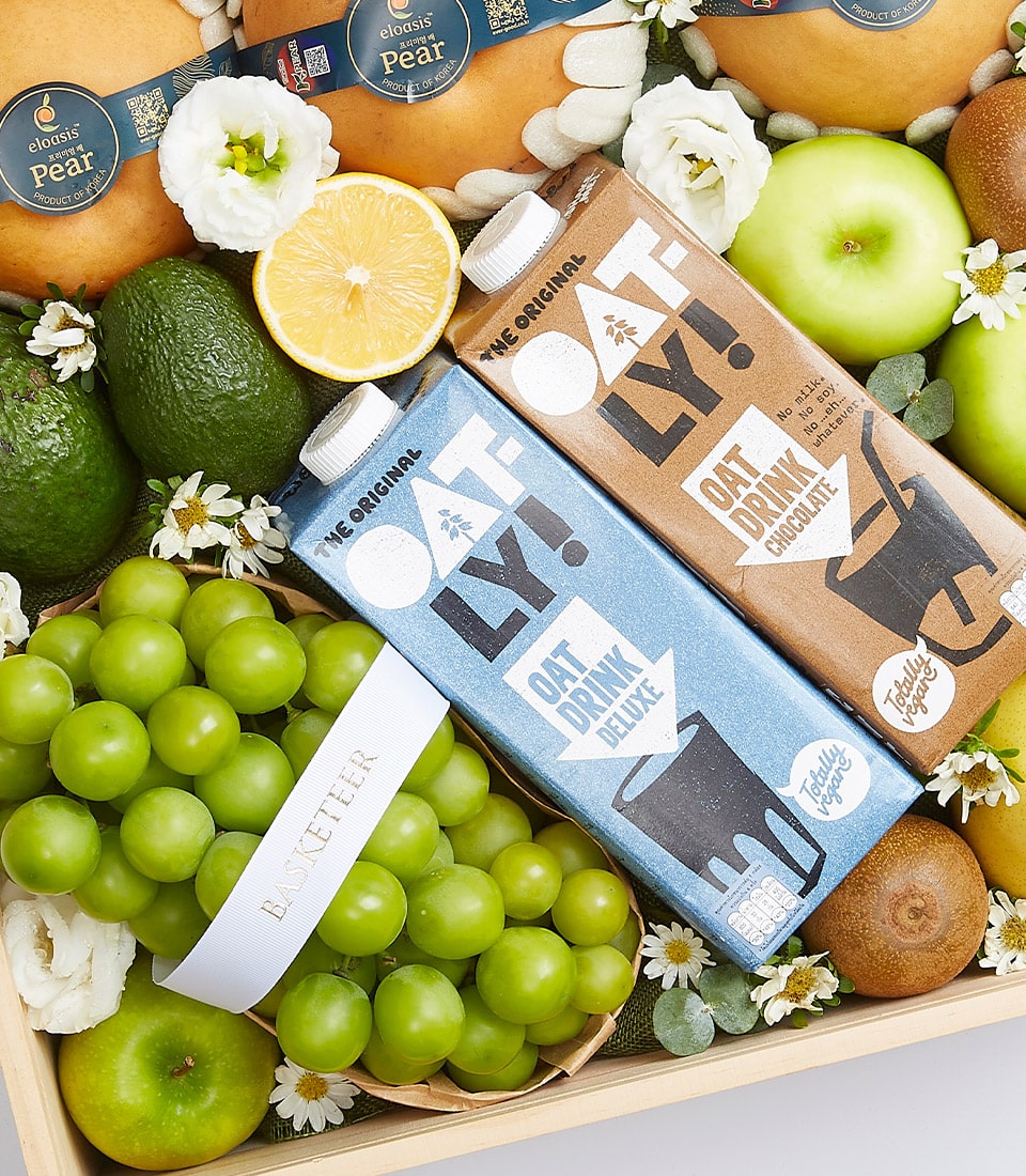 Luxury fresh fruit gift box with organic oat drinks, grapes, apples, avocados, kiwis and Asian pears on wooden tray