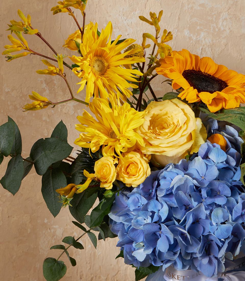 Yellow sunflowers and blue hydrangeas in a premium floral arrangement with eucalyptus greenery