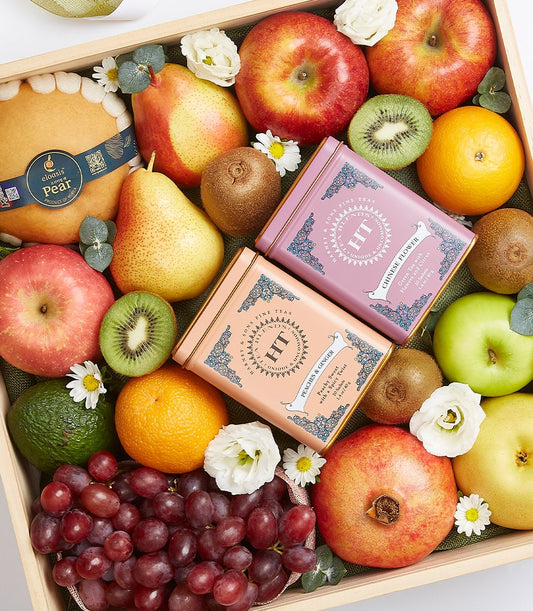 Wooden gift box with assorted fresh fruits, kiwis, apples, pears, grapes, and premium tea tins on green fabric lining