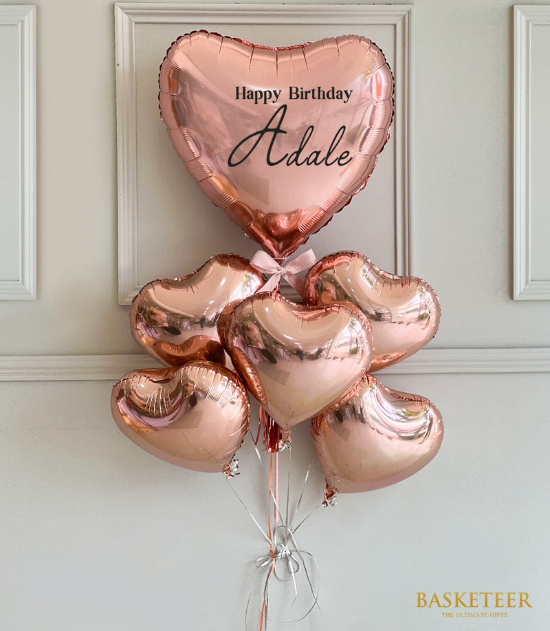 Rose gold heart-shaped foil balloons with personalized birthday message and silver ribbon bow