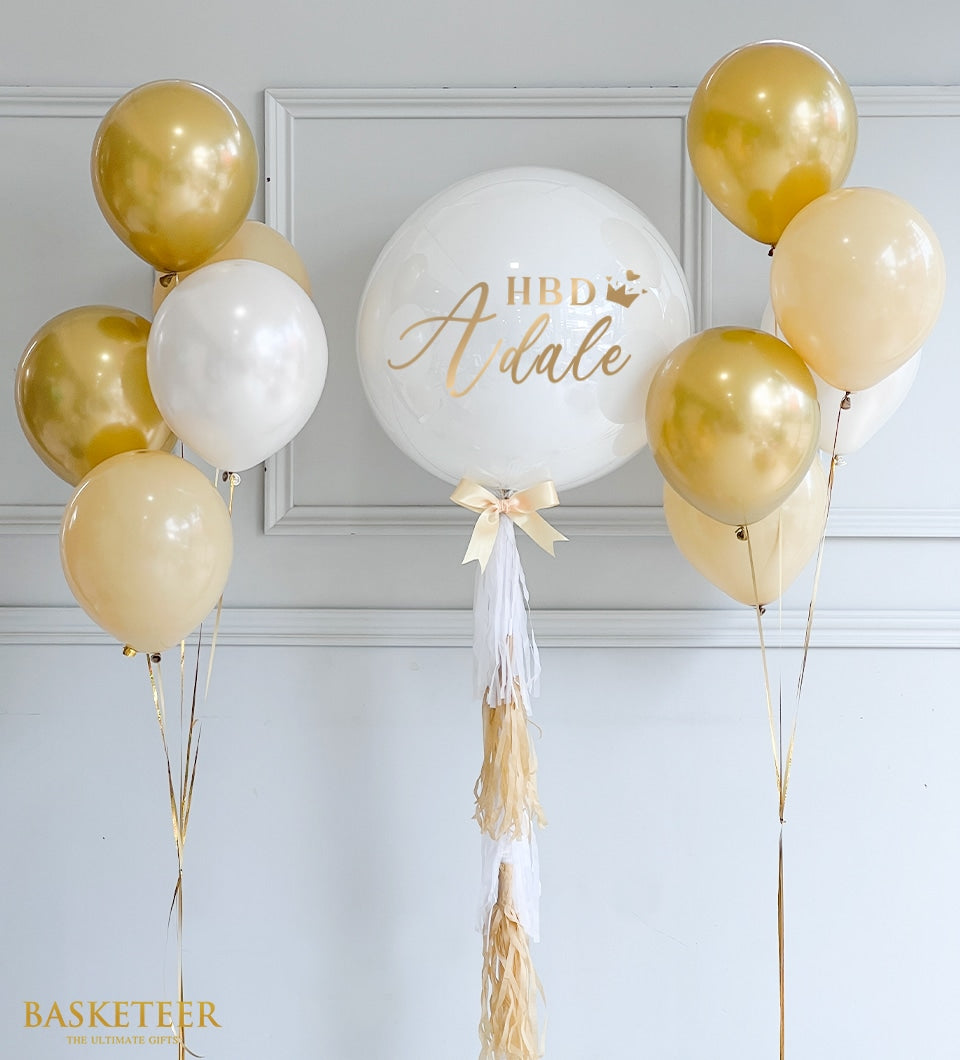 Elegant white and gold bubble balloon arrangement with personalized script and tassel ribbons for celebrations