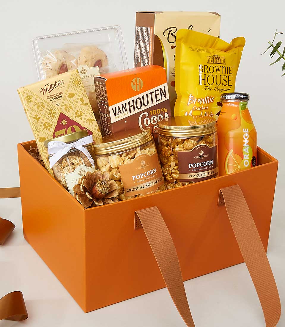 Luxury leather and gourmet food gift hamper with chocolates, popcorn, crackers, and artisan treats in orange gift box