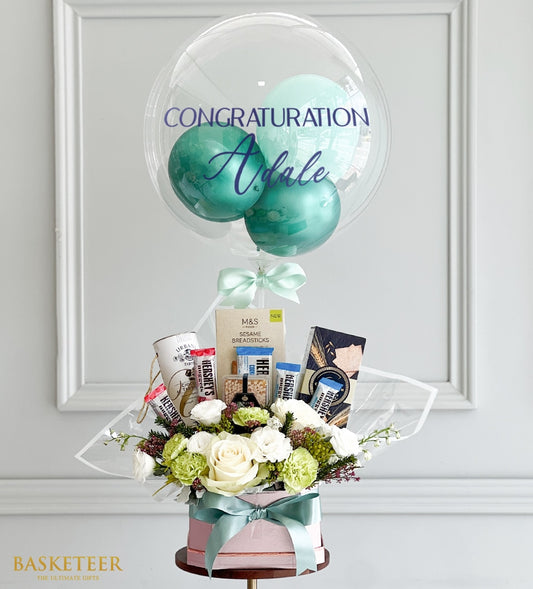 Personalized congratulations balloon gift set with white flowers, chocolates, and gourmet snacks in mint green box