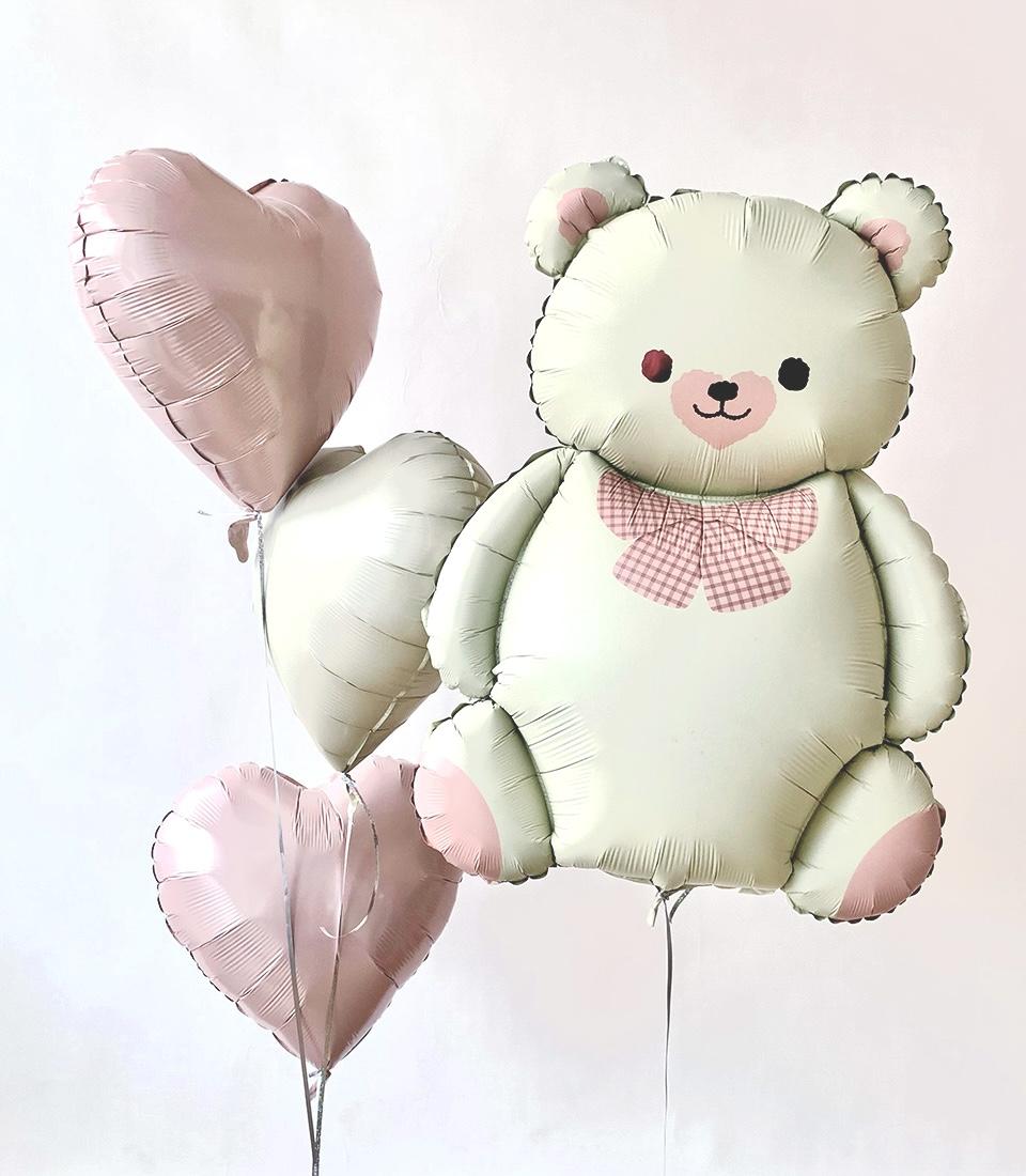 Light green teddy bear foil balloon with pink bow tie, paired with soft pink and green heart balloons