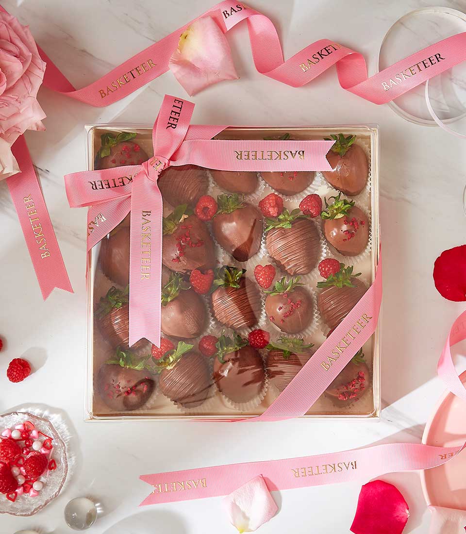 Deluxe chocolate-covered strawberries gift box with milk chocolate drizzle and raspberries, tied with pink ribbon