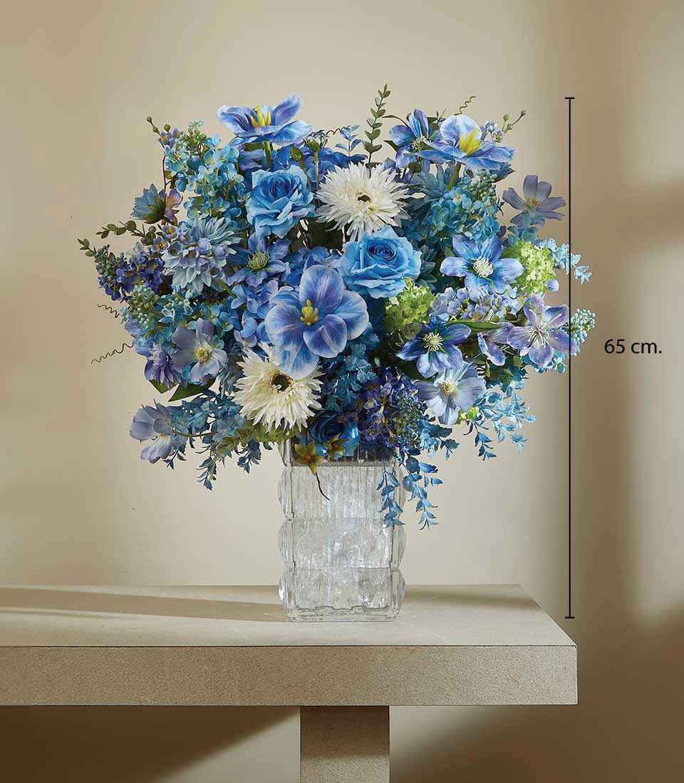 Tall blue artificial flower arrangement with roses and dahlias in textured glass vase