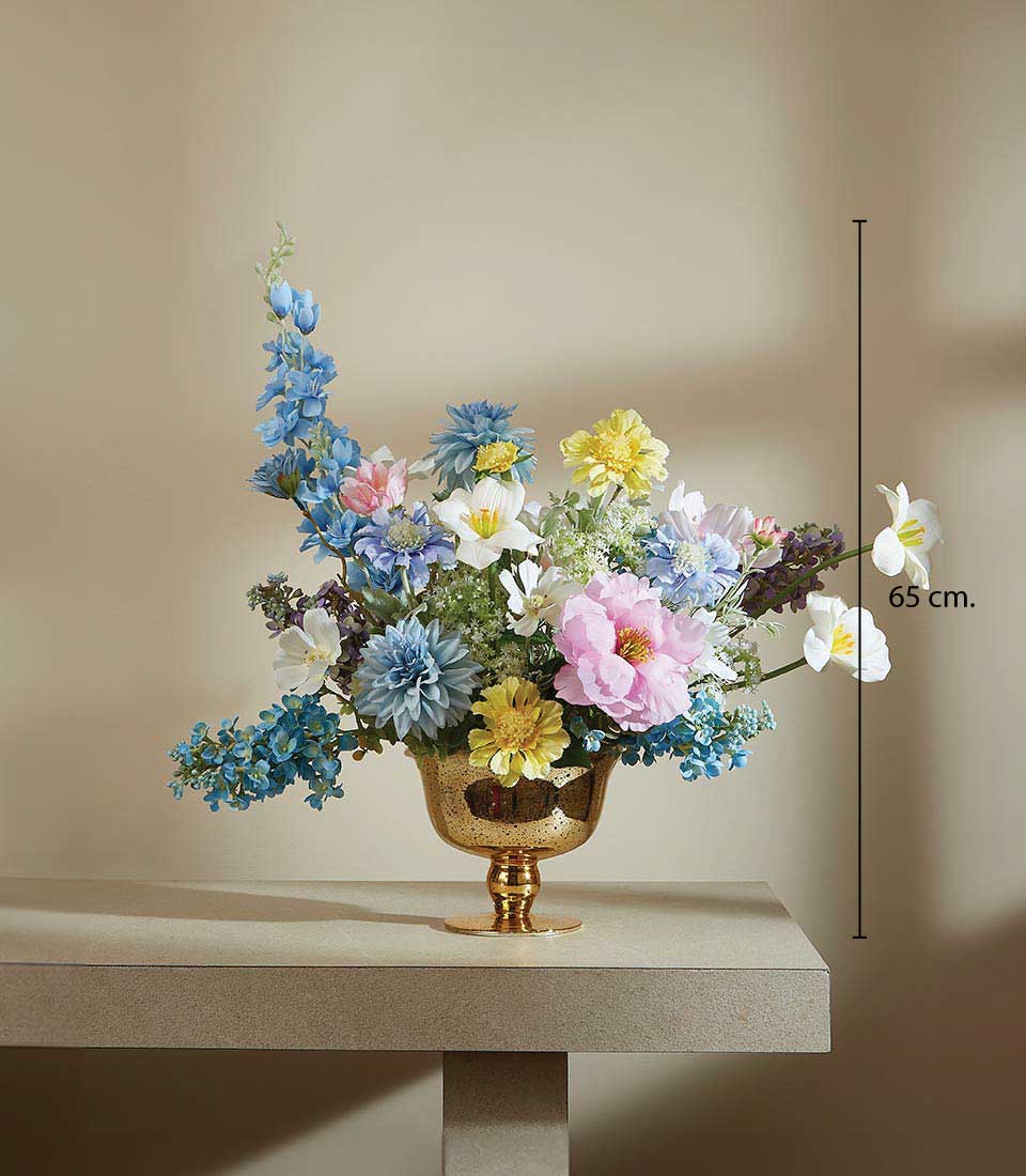 Vibrant mixed artificial flower arrangement with blue delphiniums, pink peonies, and yellow dahlias in gold footed bowl