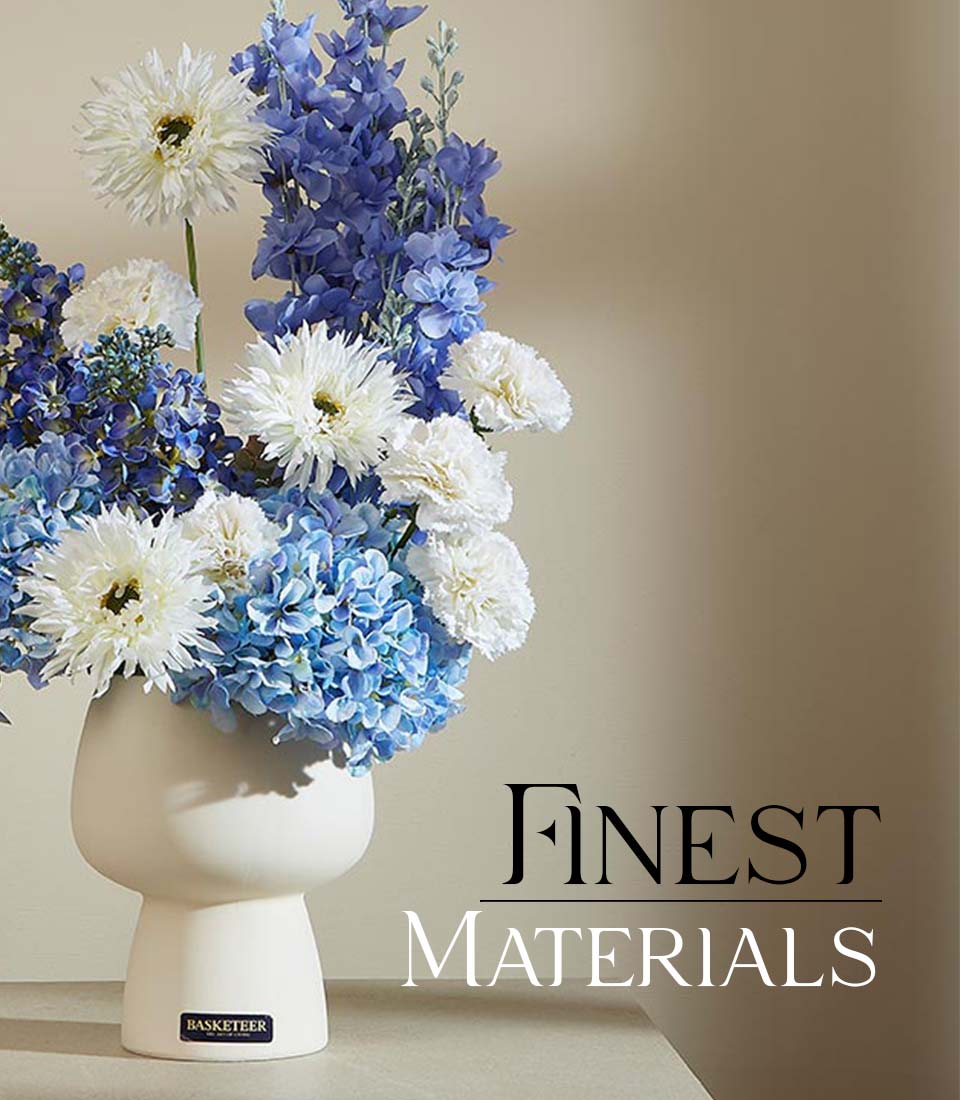 Blue and white artificial flower arrangement in modern matte white ceramic vase with delphiniums and hydrangeas