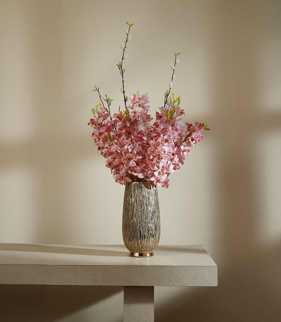 Tall gold and grey vase with vibrant pink flower arrangement and pussy willow branches