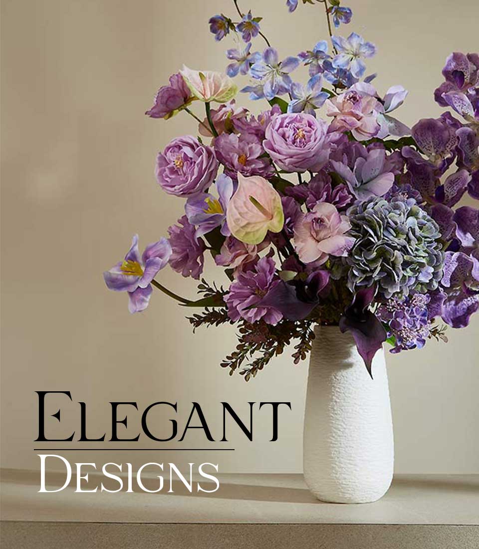 Purple and lavender artificial flower arrangement in white ceramic vase with roses, orchids, and hydrangeas