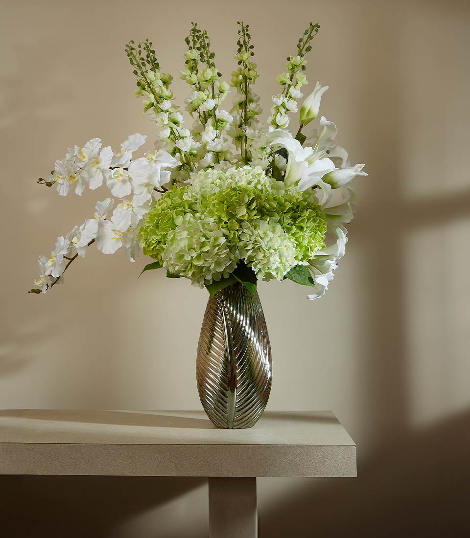 White orchids, lilies, and hydrangeas in bronze-gold textured vase, elegant artificial flower arrangement