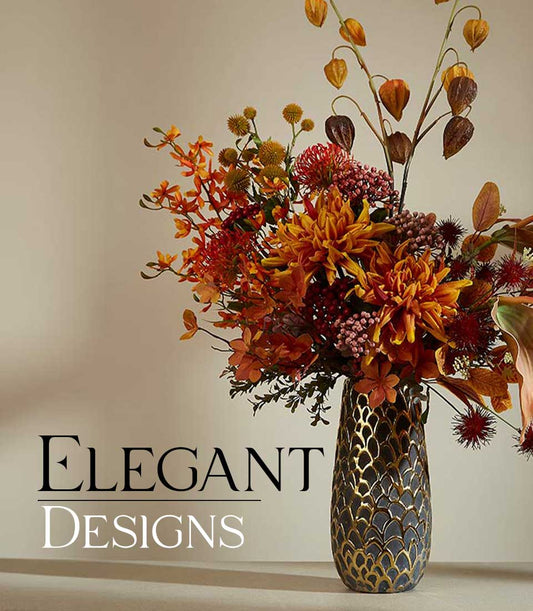 Autumnal artificial flower arrangement with orange dahlias, orchids, and dried seed pods in gold-patterned vase
