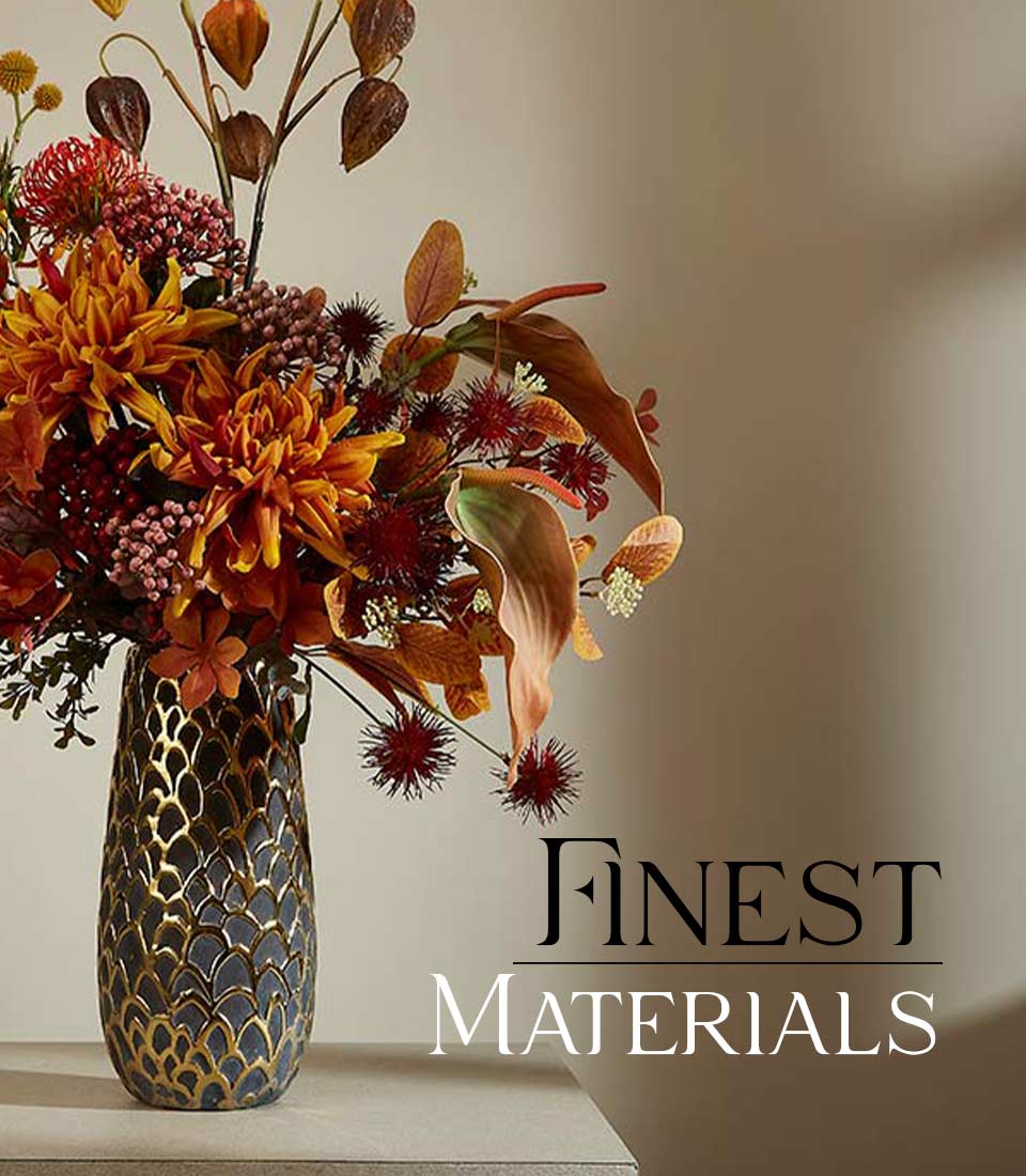 Autumnal artificial flower arrangement with orange dahlias and red blooms in dark gold-patterned ceramic vase