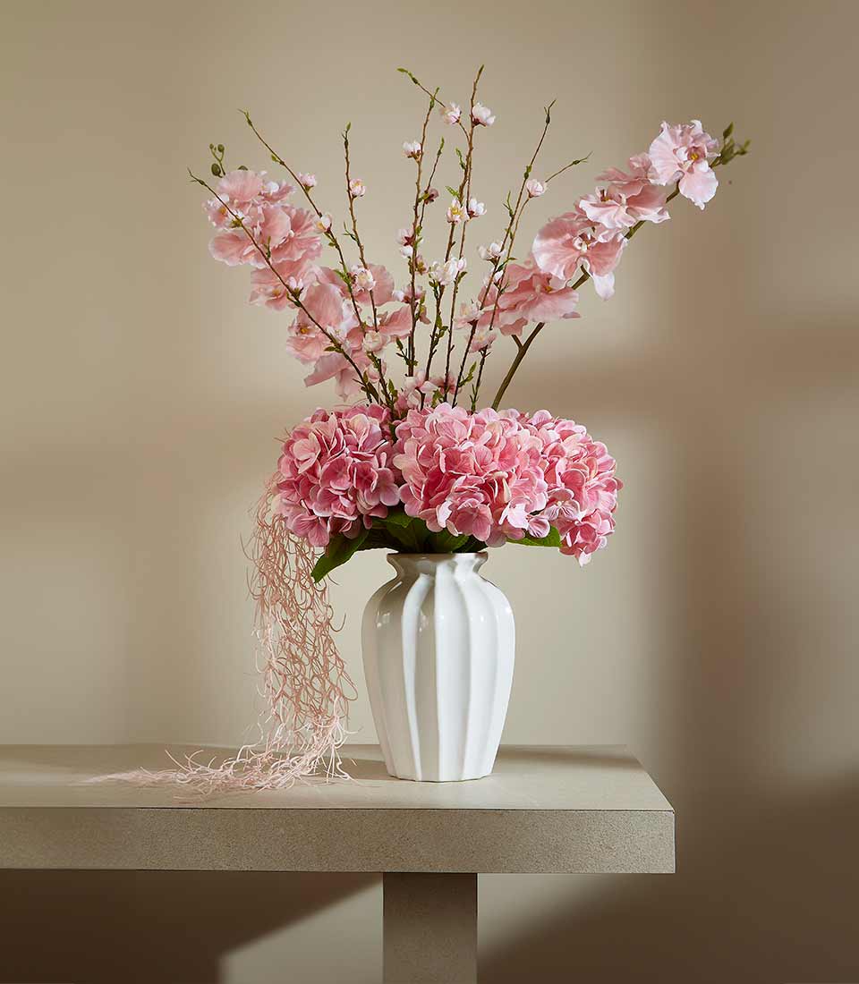 Charming pink artificial flower vase with hydrangeas, cherry blossoms, and orchids in white ceramic