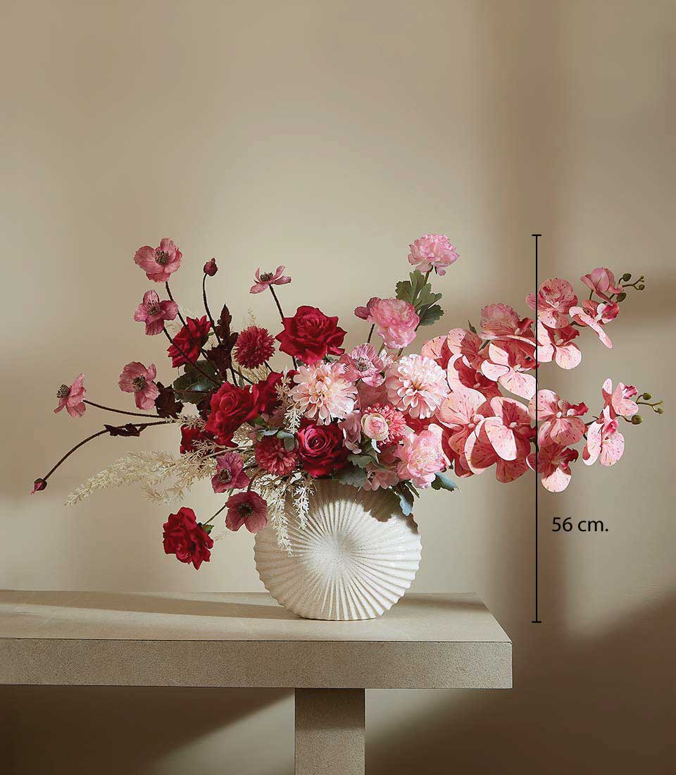 Romantic Charm artificial flower vase with red and pink roses, dahlias, and feathery foliage in cream ceramic ribbed vessel,