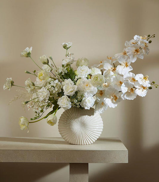 Frosted white and cream artificial flower arrangement with orchids and roses in textured ceramic vase