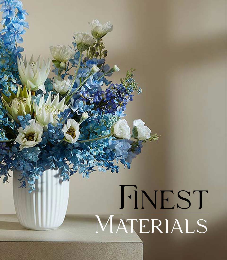 Serenity Blossom artificial flower vase with blue delphiniums, hydrangeas and white ranunculus in white ceramic ribbed vase