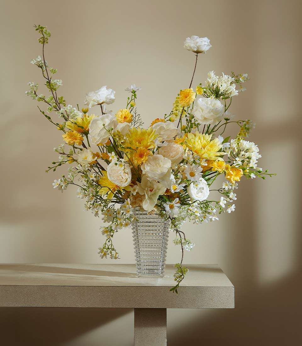 Premium white and yellow artificial flower arrangement in textured glass vase with roses, dahlias, and greenery