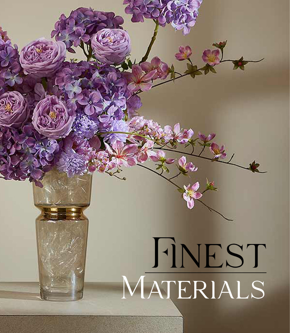 Tall clear glass vase with gold neck band holding purple hydrangeas, lavender roses, and pink blossoms arrangement