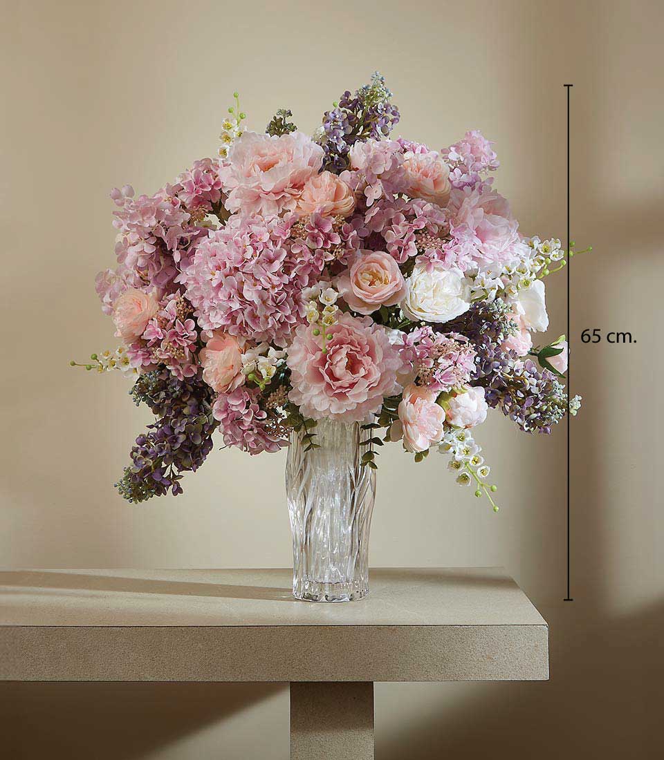 Tall artificial flower arrangement with pink peonies, hydrangeas, and white blooms in textured glass vase