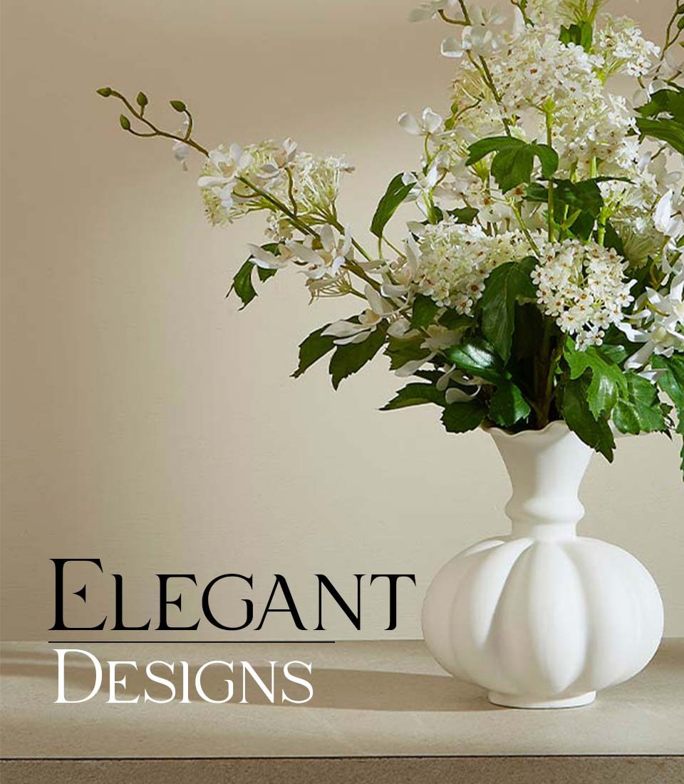 White ceramic vase with artificial white flowers and green foliage arrangement