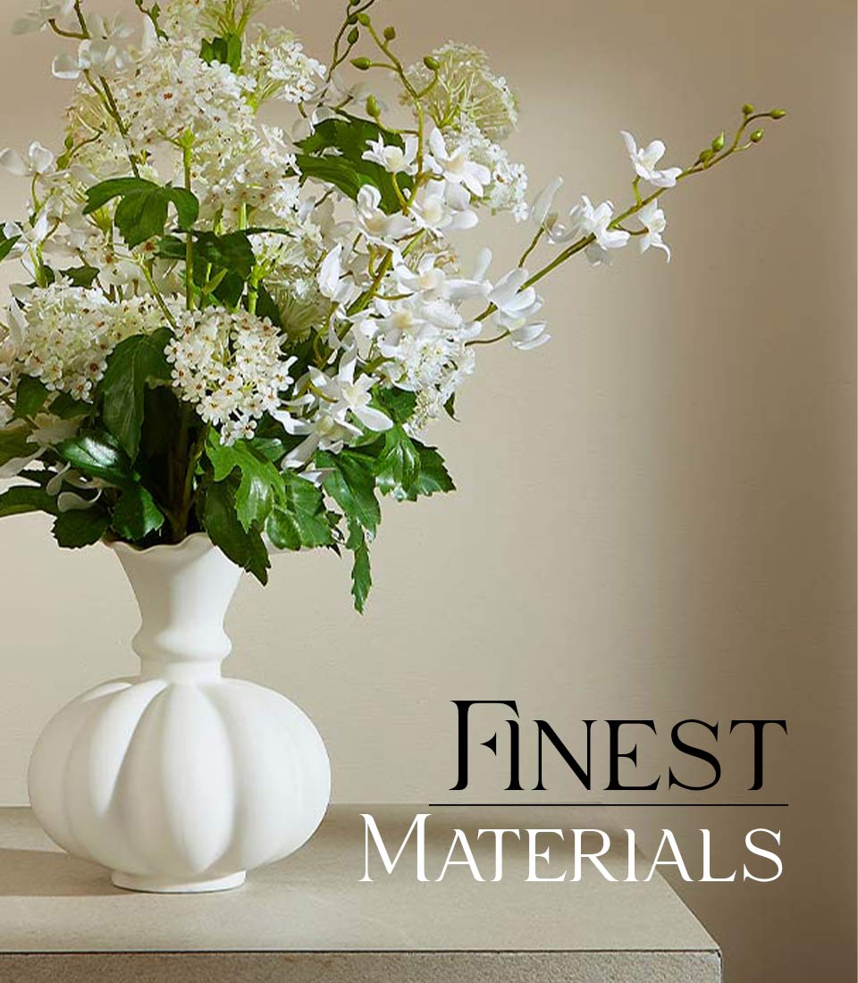 White ceramic vase with artificial hydrangea and orchid arrangement, green foliage, ruffled rim