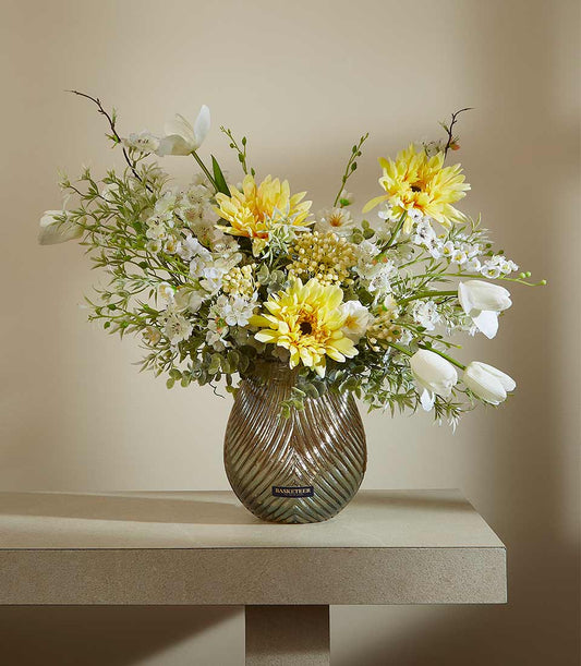 Sunny Serenity artificial flower arrangement with yellow dahlias, white tulips, and greenery in textured grey-brown vase