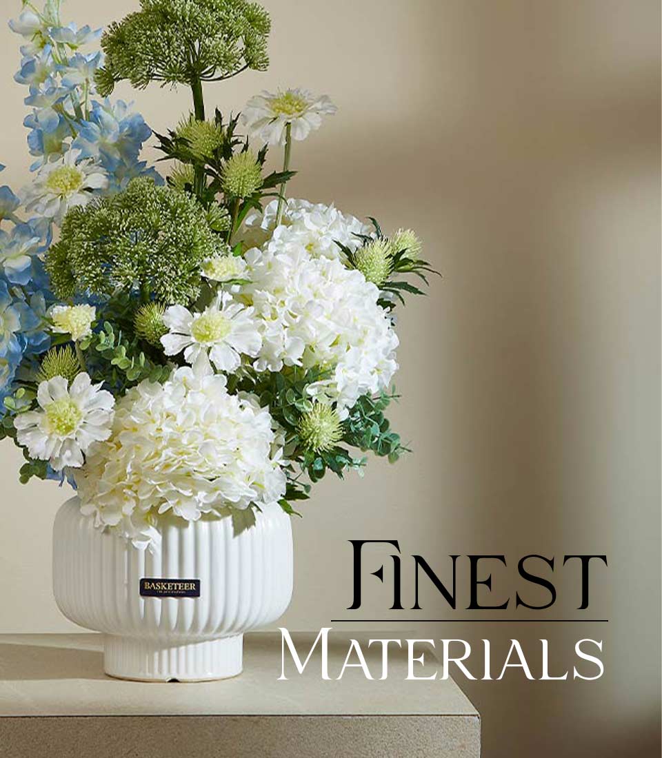 White hydrangeas and delphiniums in ribbed ceramic vase, artisan floral arrangement with green foliage
