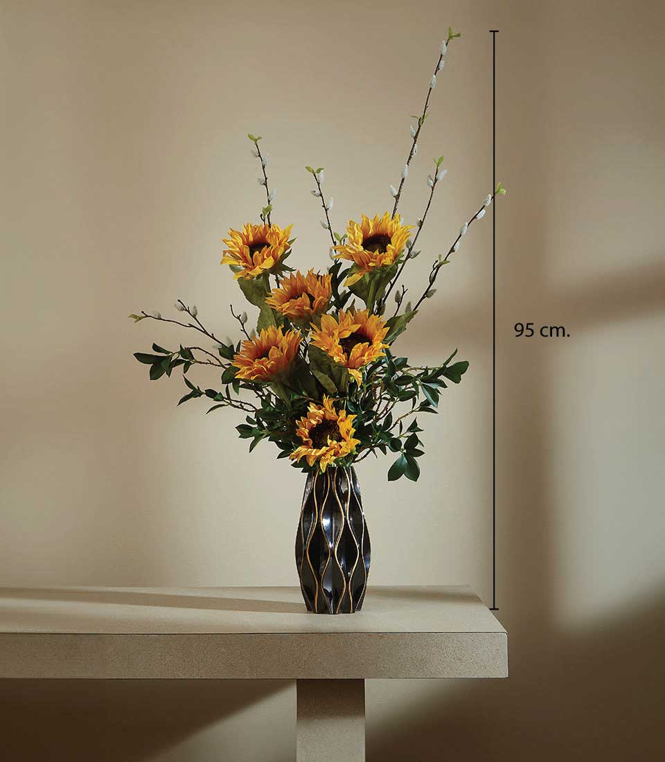 Tall artificial sunflower vase arrangement with yellow blooms, green foliage, and textured gold-patterned black vase
