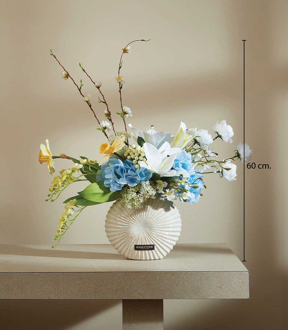 Cream ceramic vase with white lilies, light blue hydrangeas, and yellow daffodils artificial flower arrangement