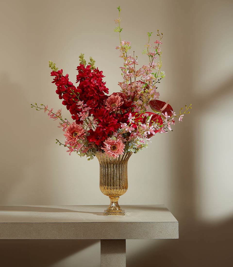 Scarlet luxury artificial flower arrangement in gold ribbed urn vase with deep red, fuchsia, and pink blooms