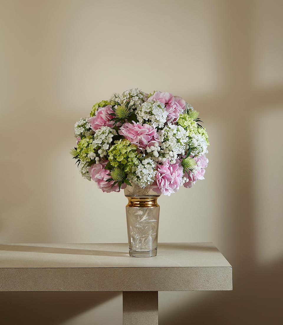 Elegant springtime artificial flower arrangement with pink carnations, white baby's breath, and green hydrangeas in