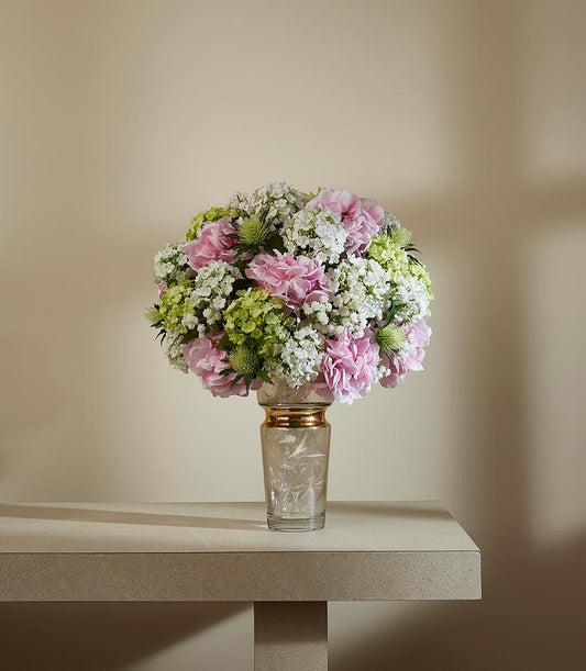 Elegant springtime artificial flower arrangement with pink carnations, white baby's breath, and green hydrangeas in