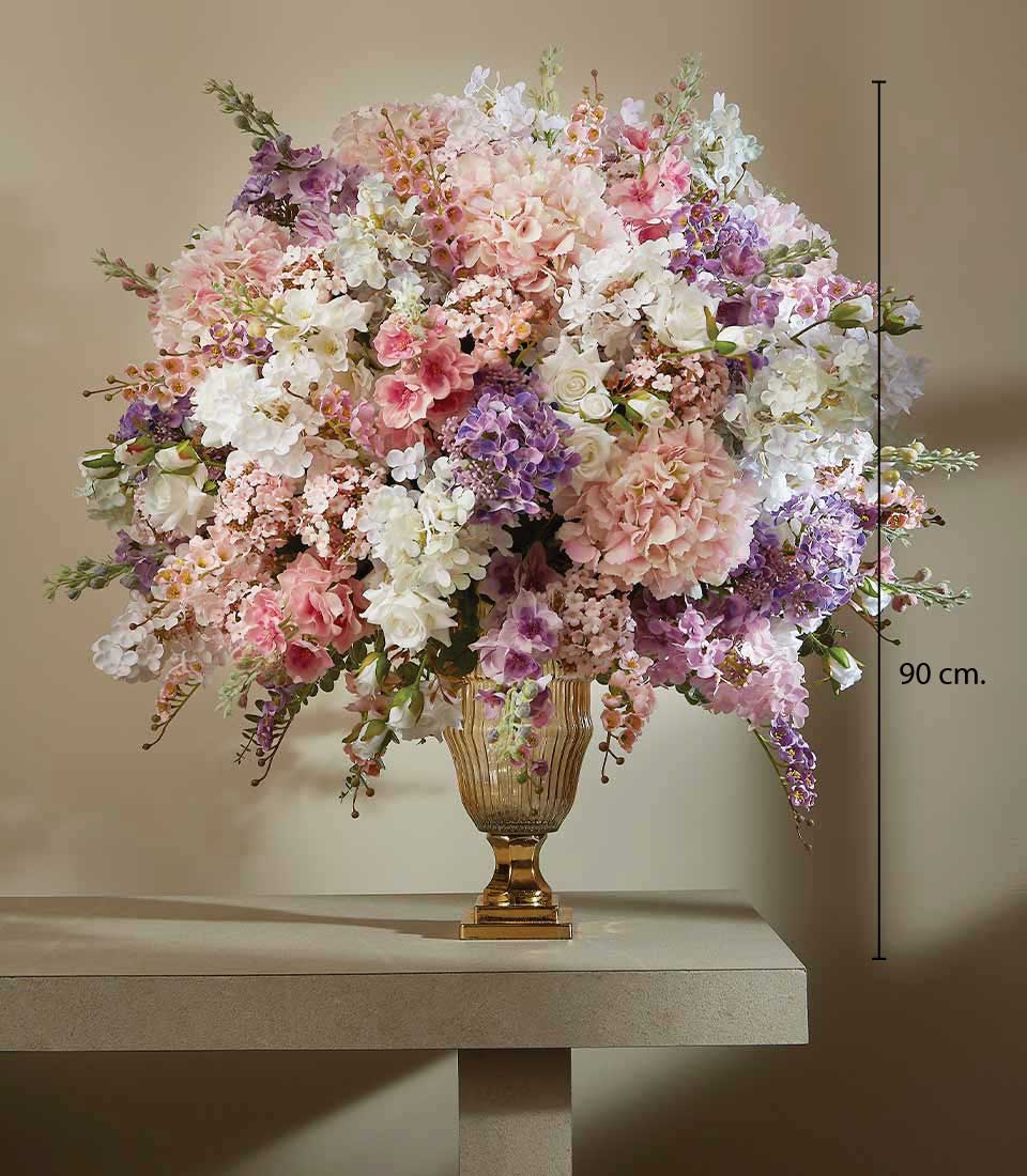 Luxurious large artificial flower arrangement in pink, lavender, and white roses with hydrangeas in golden urn vase