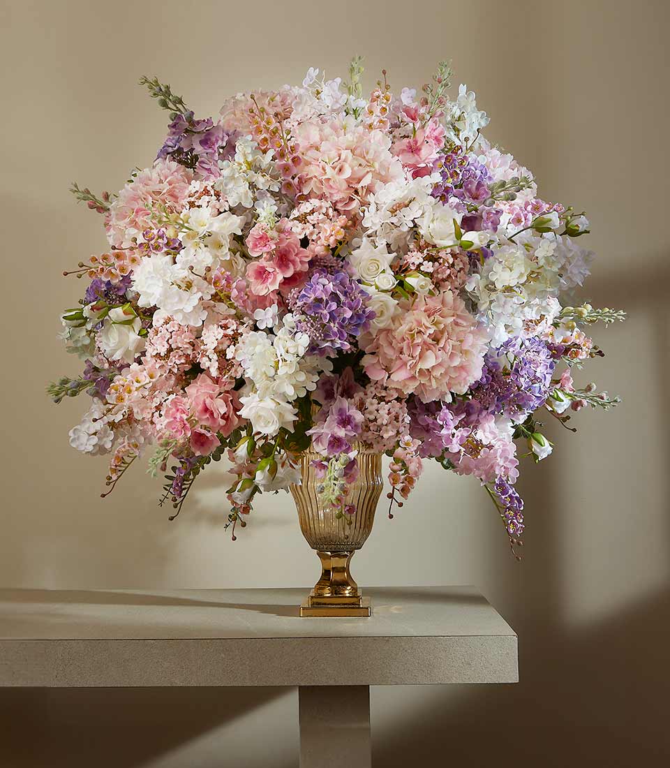 Luxurious large artificial flower arrangement in pink, lavender, and white with amber glass vase and gold pedestal base