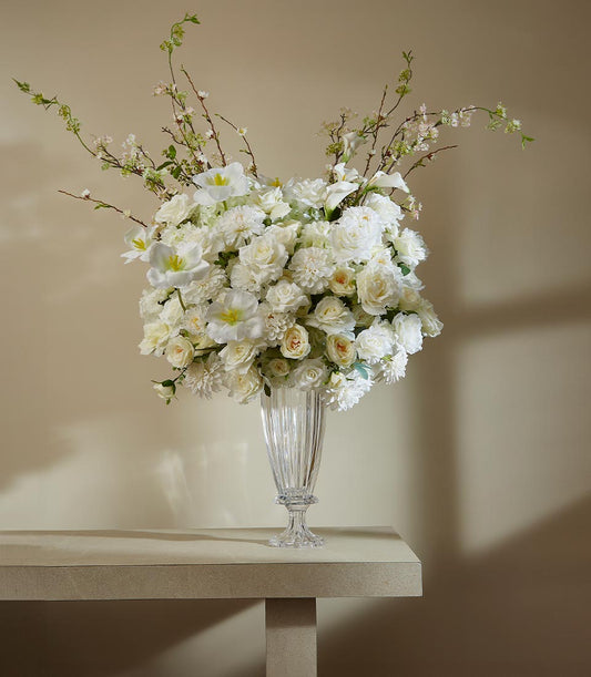 White roses, dahlias, and tulips in tall fluted vase with lush artificial flower arrangement
