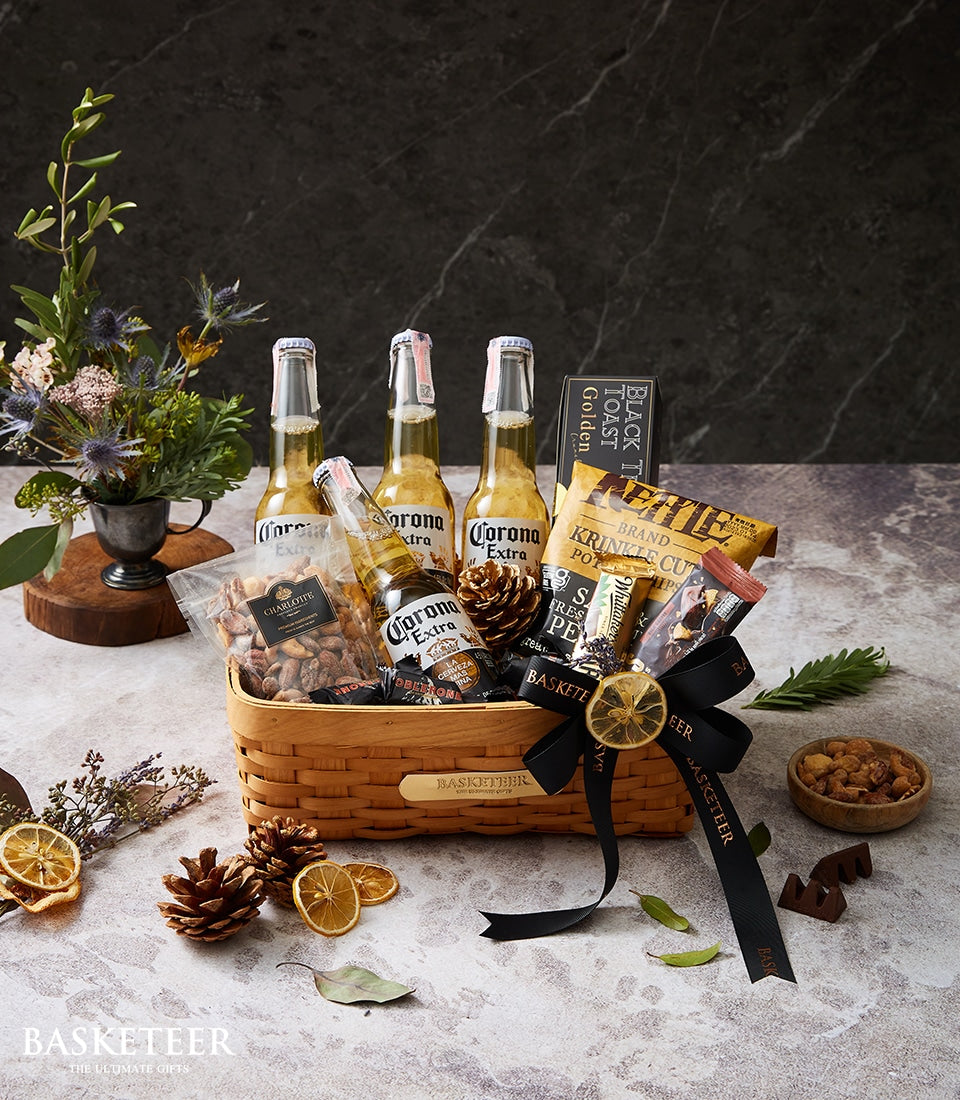 Premium Corona beer and savoury snacks in woven gift basket with black ribbon bow