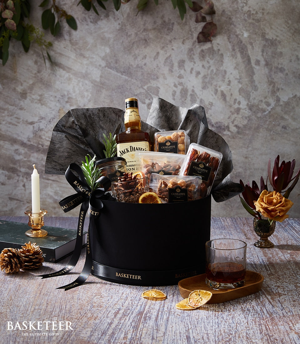 Luxury Jack Daniel's whiskey gift box with gourmet snacks, nuts, and dried fruit on dark grey tissue