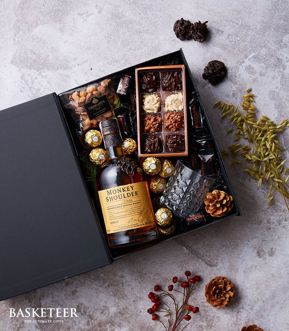 Luxury whisky gift box with Monkey Shoulder Scotch, geometric glass, artisan chocolates, nuts, and truffles