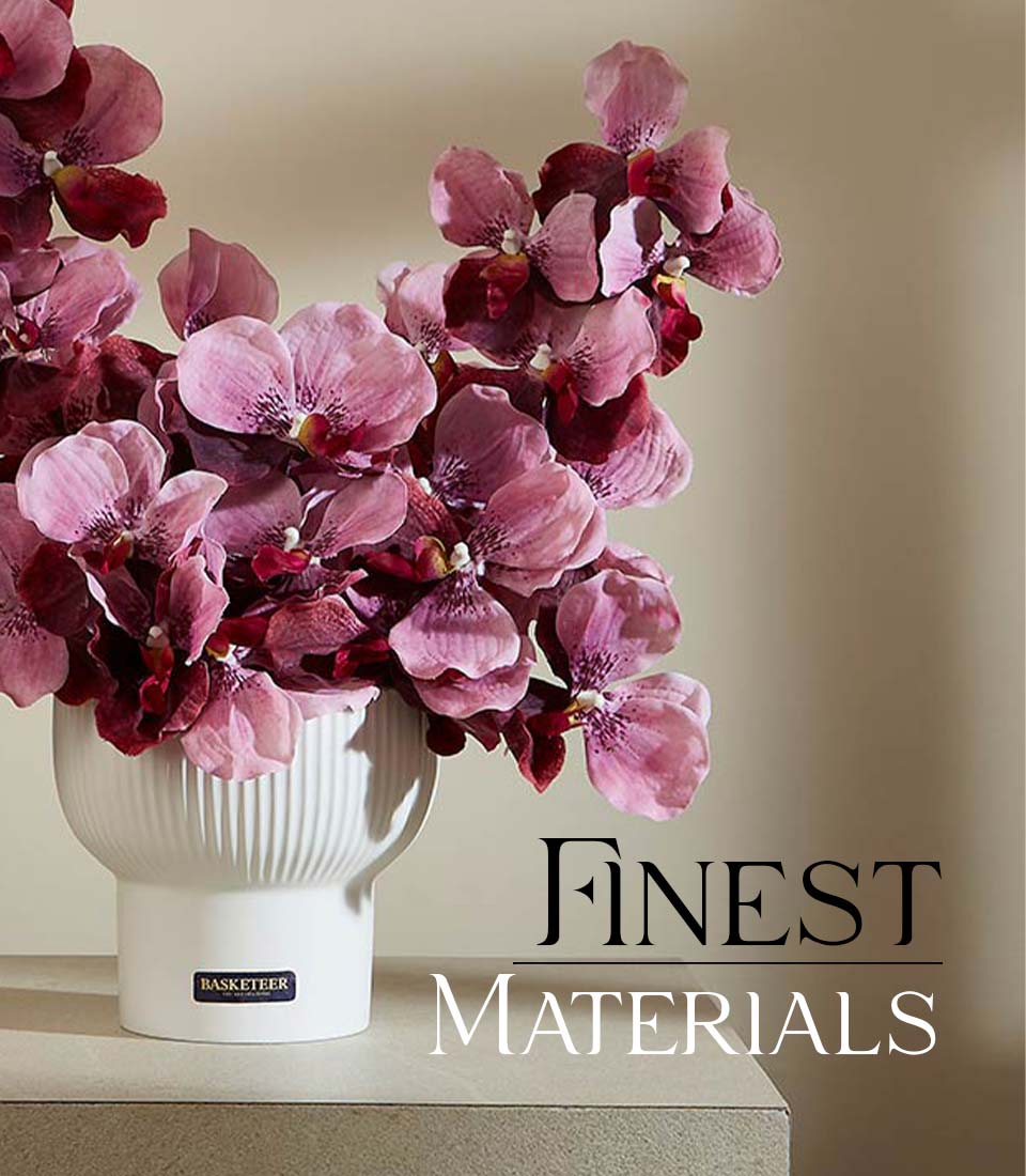 Soft pink artificial orchids with deep purple centers in white fluted ceramic vase
