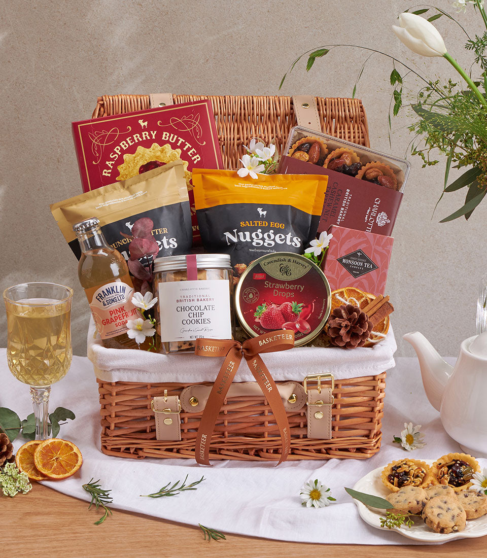Woven wicker gourmet gift basket with raspberry butter, salted egg nuggets, chocolate chip cookies, strawberry drops, pink