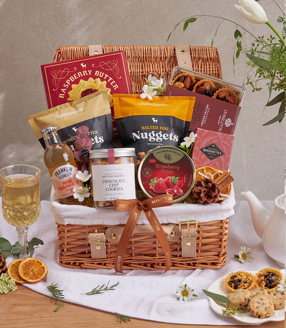 Wicker picnic basket luxury gift hamper with gourmet cookies, tea, soda, and artisan snacks