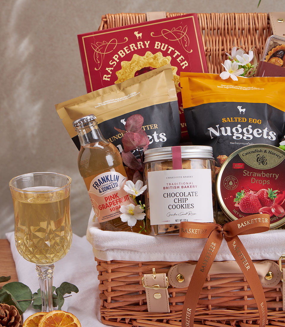 Luxury wicker gift basket with gourmet treats, premium snacks, raspberry butter, artisan cookies, and pink grapefruit soda