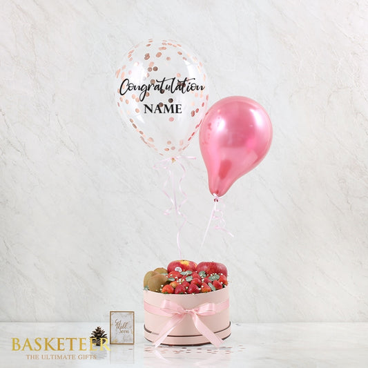 Fresh fruit gift box with congratulations balloons in rose gold and pink