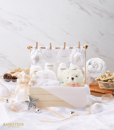 Newborn baby gift set in wooden crate with organic care products, white teddy bear, and miniature clothing