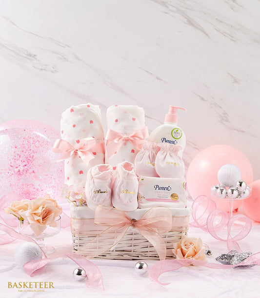 Pink and white newborn gift basket with polka dot blankets, baby lotion, wipes, booties, and mittens