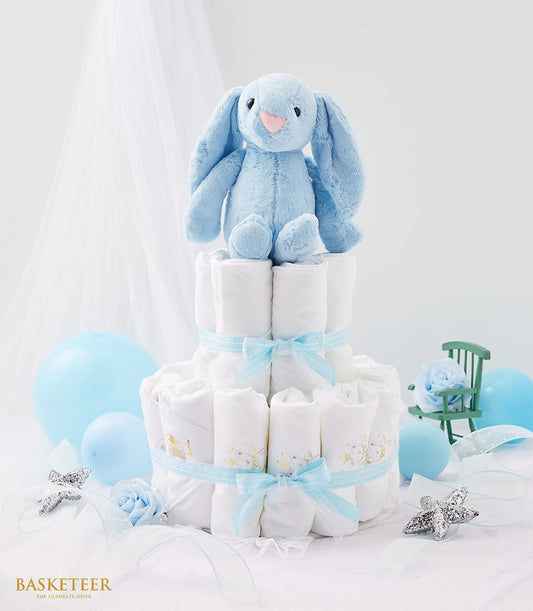 Light blue two-tier newborn diaper cake with plush bunny, satin ribbons, and star decorations for baby boy gift