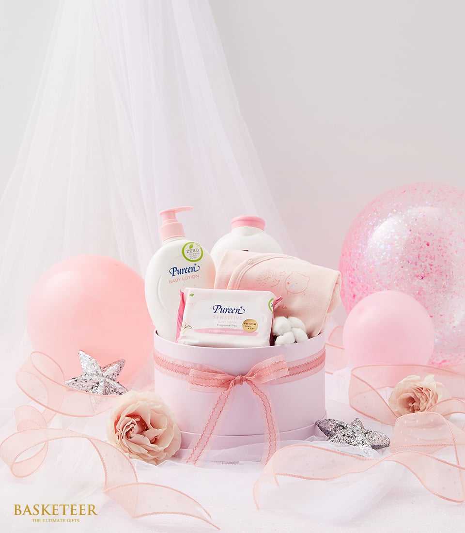 Luxe newborn arrival gift set in blush pink box with baby care essentials, soft ribbons, and glitter balloons