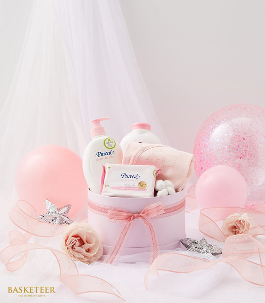 Luxe newborn arrival gift set in blush pink box with baby care essentials, soft ribbons, and glitter balloons