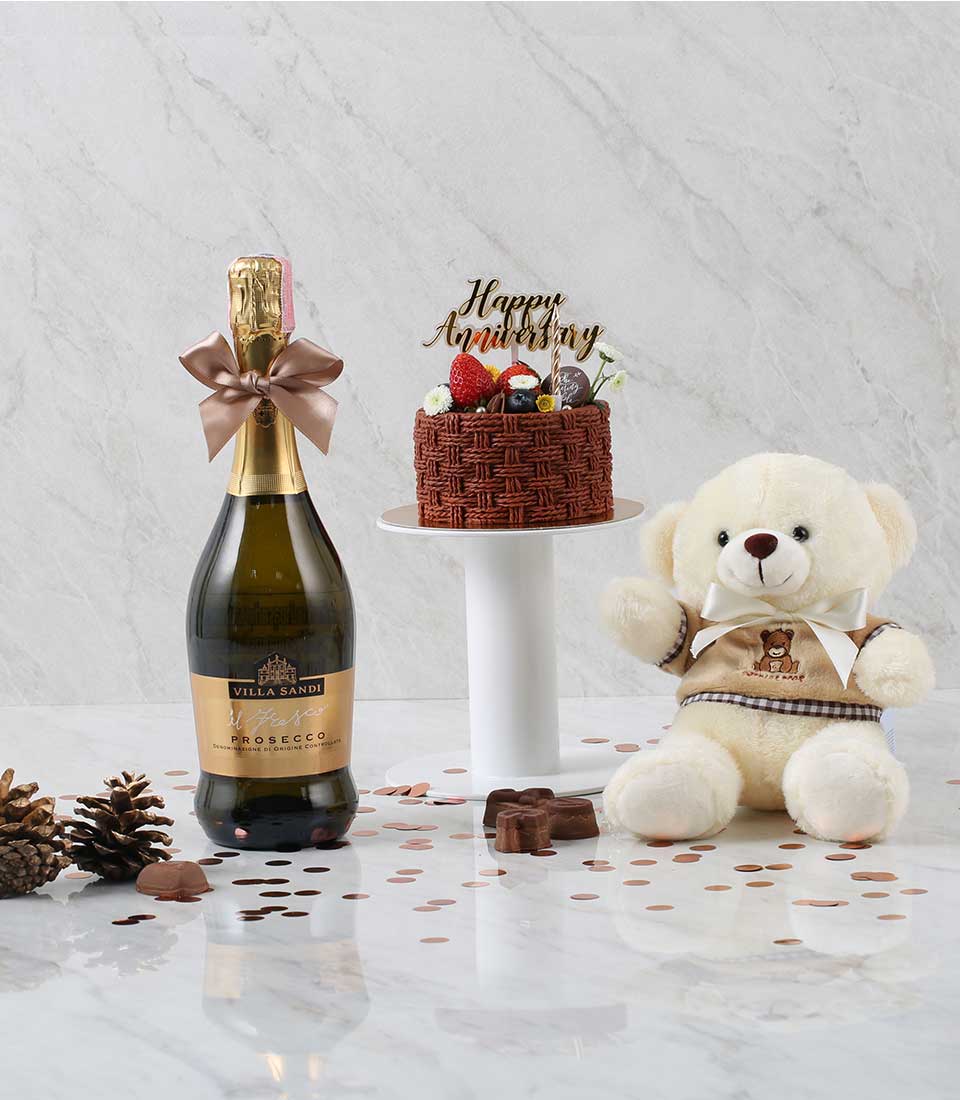 Prosecco bottle with chocolate cake, fresh berries, and teddy bear gift set for anniversary celebrations